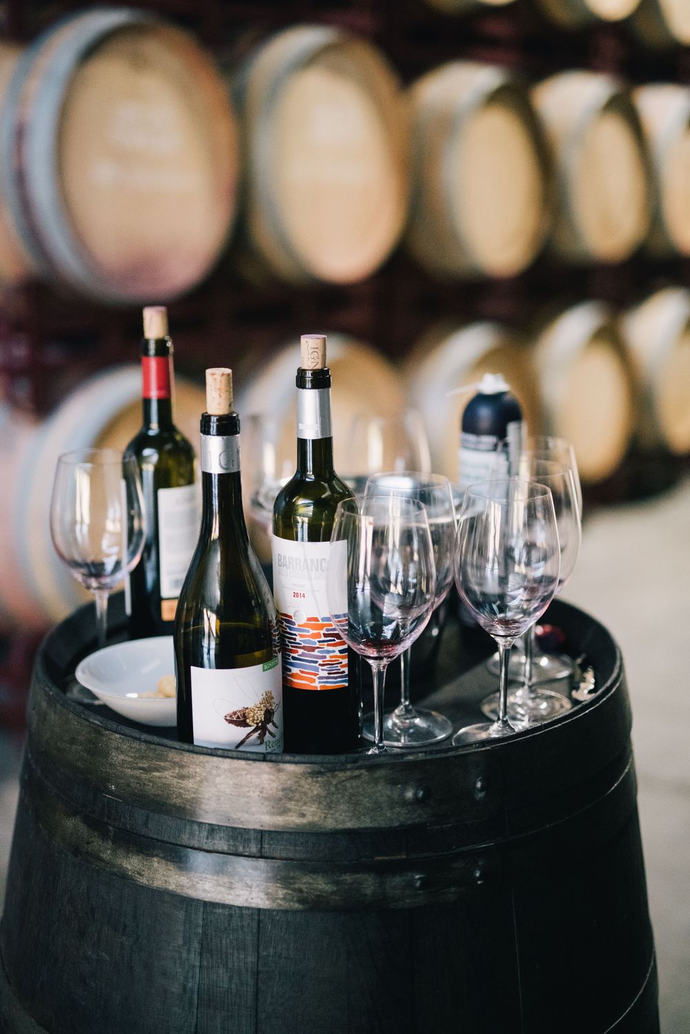 Wine bottles and glasses arranged on a barrel in a cellar